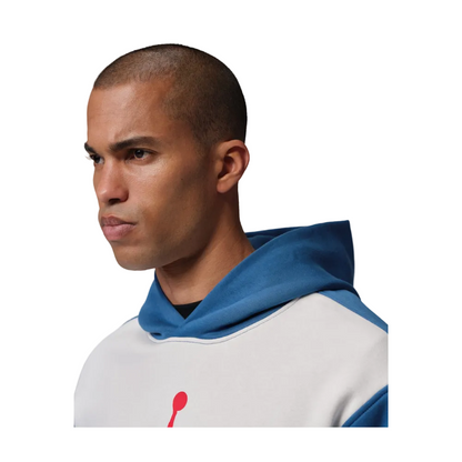 A man in profile wearing a white and blue pullover hoodie with a red Jumpman logo on the chest, set against a solid gray studio background.