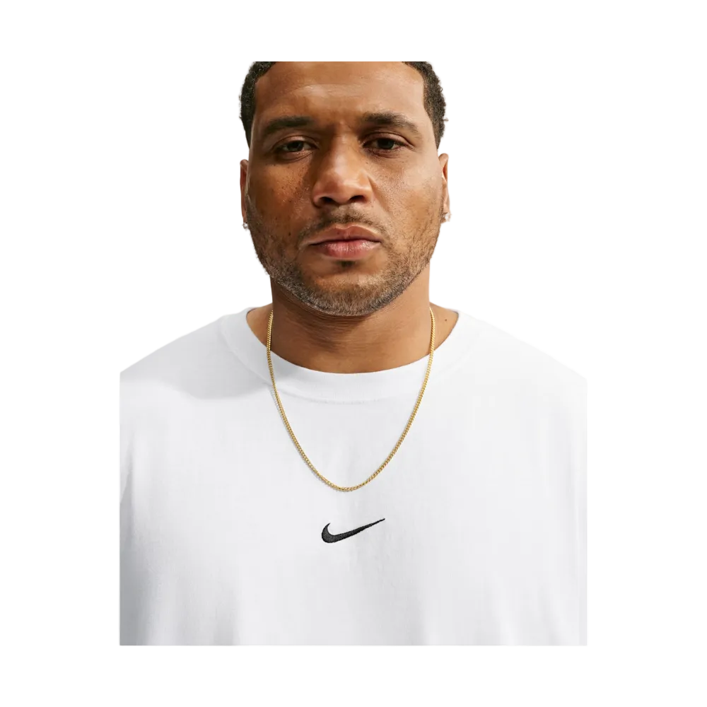 A man wearing a white crewneck t-shirt with a black Nike swoosh logo on the chest, accessorized with a gold chain necklace, set against a light gray background.
