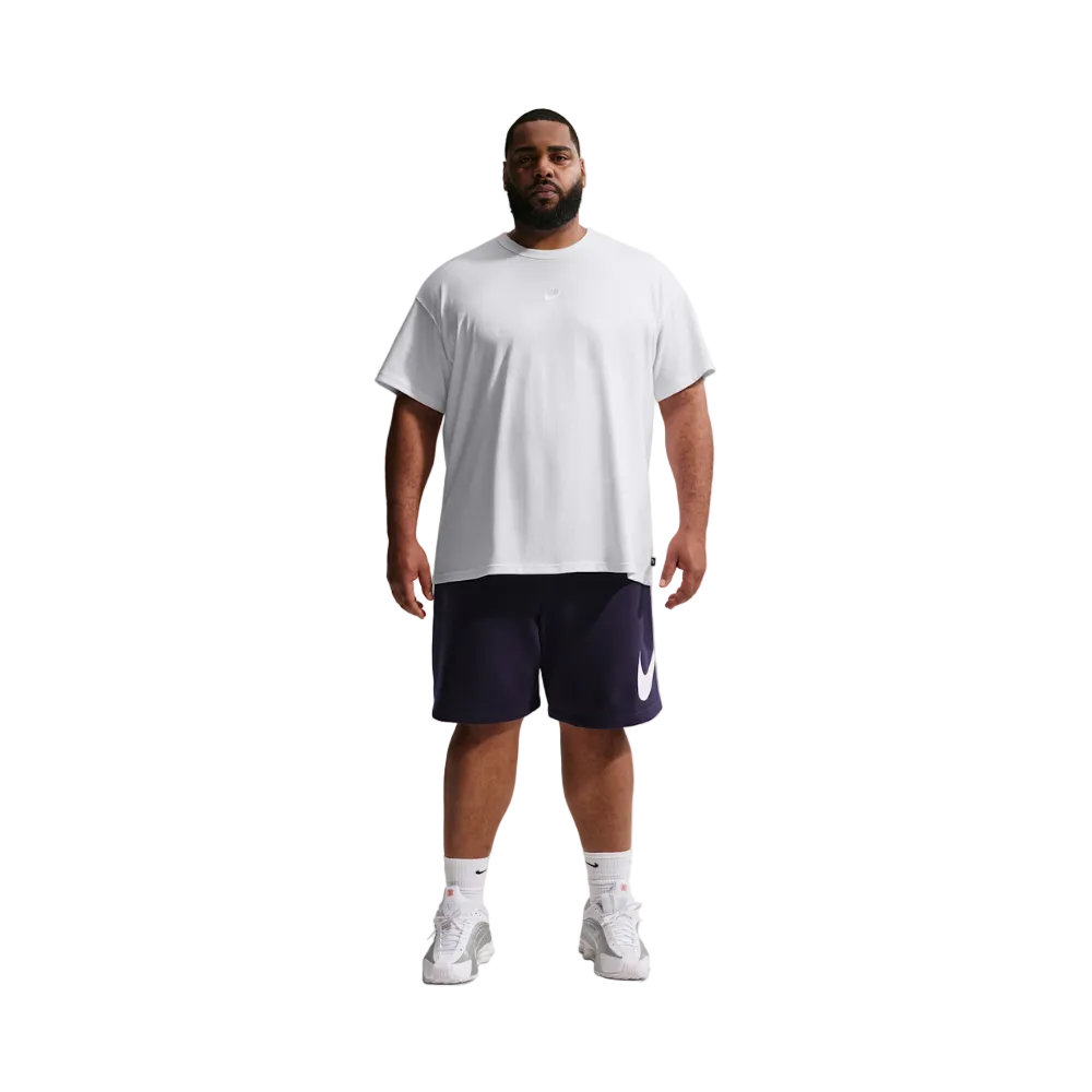 A man modeling a white Nike short-sleeve t-shirt and navy blue athletic shorts with a white Swoosh logo, paired with white socks and sneakers, against a light gray studio background.