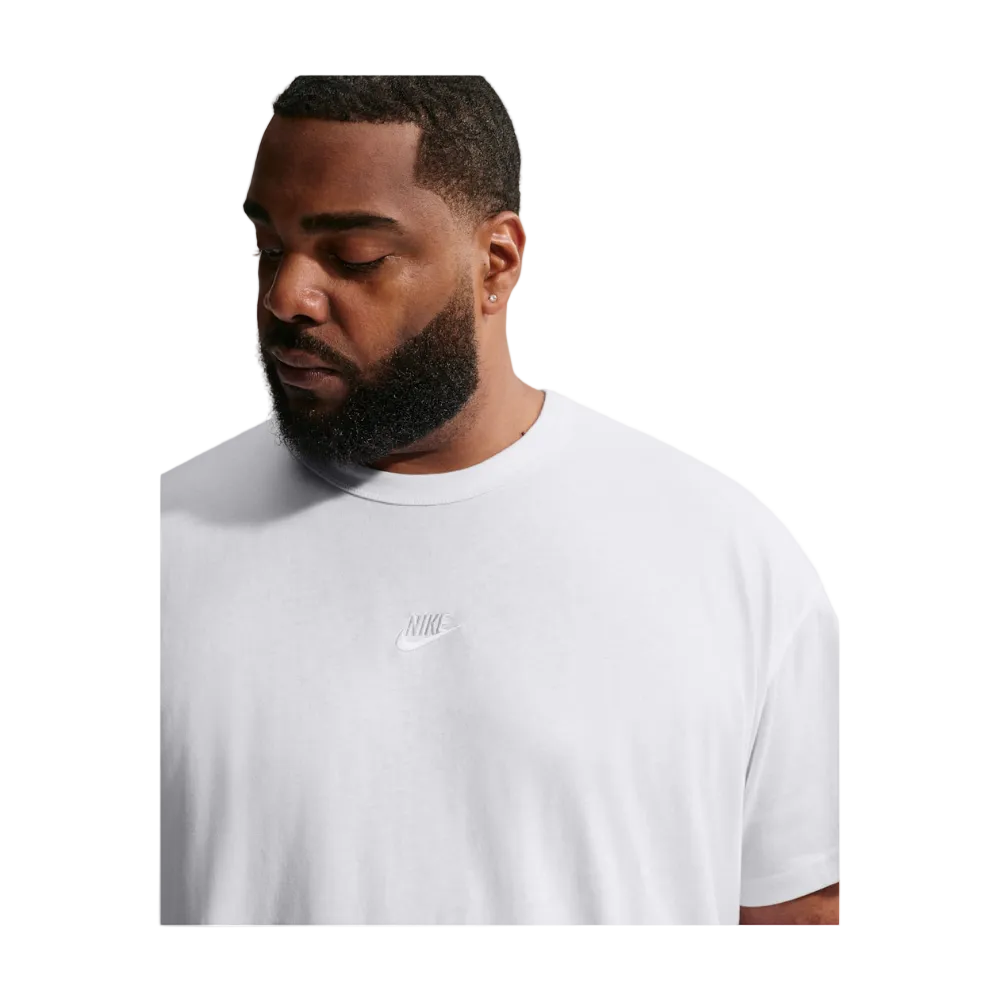 A man wearing a white crew-neck t-shirt with a subtle tonal Nike logo on the chest, shown in a close-up profile view against a light gray background.