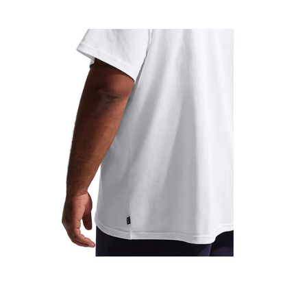 A close-up side view of a person wearing a plain white short-sleeve T-shirt, showing the side seam and a small black brand tab near the hem.