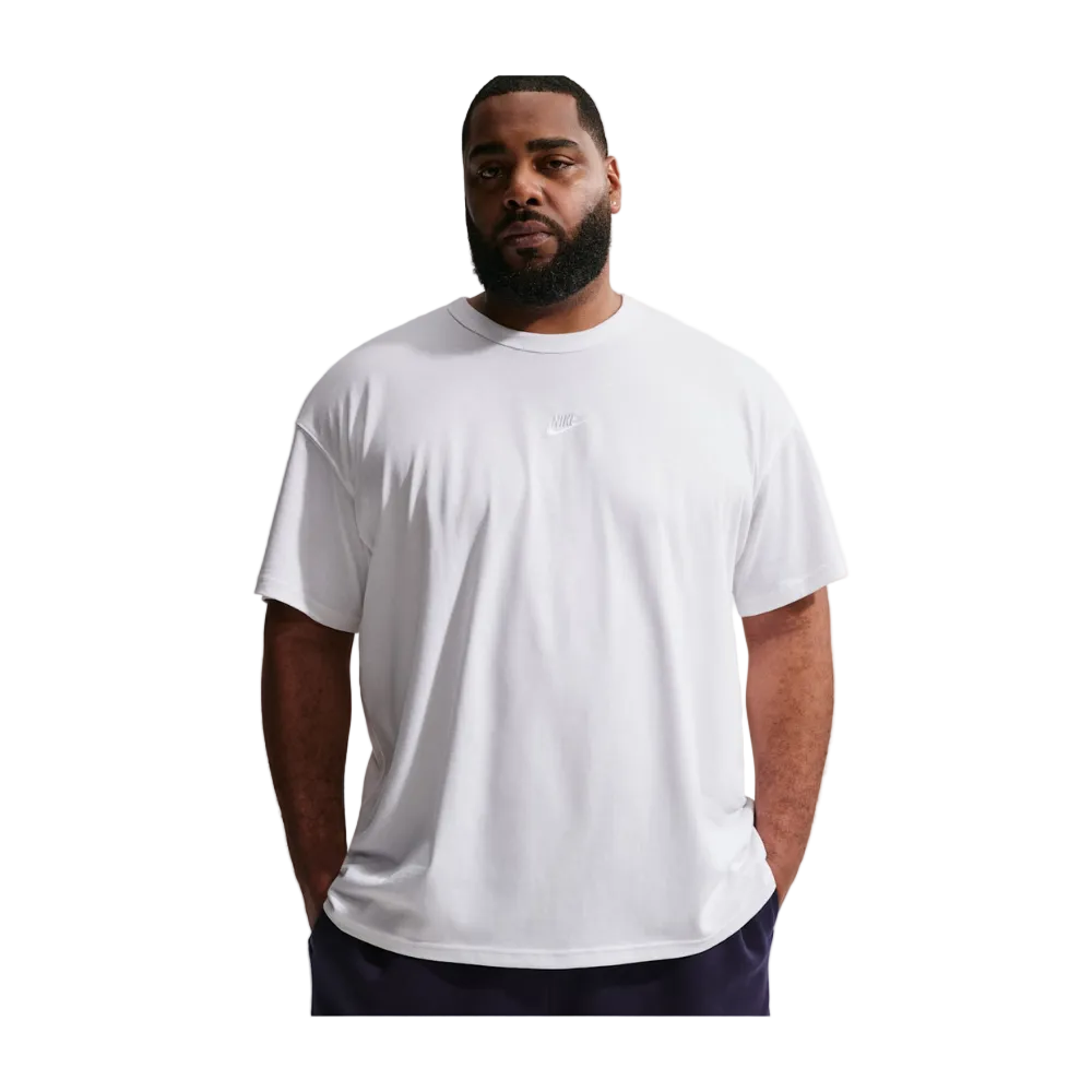 A man wearing a white short-sleeve crewneck t-shirt with a small tonal Nike logo on the left chest, photographed against a light gray studio background.