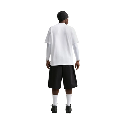A model shown from the back wearing a white short-sleeve polo shirt over a white long-sleeve base, paired with black shorts, white socks, and black shoes, against a light gray studio background.