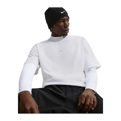 A man wearing a white Nike long-sleeve mock neck shirt, black athletic shorts, and a black beanie with a white Nike swoosh, seated against a light gray background.